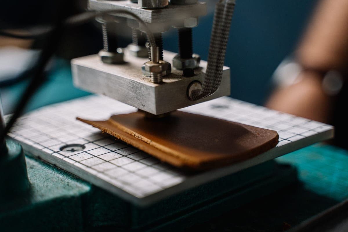 A craft cutting machine on a home workbench with paper and tools