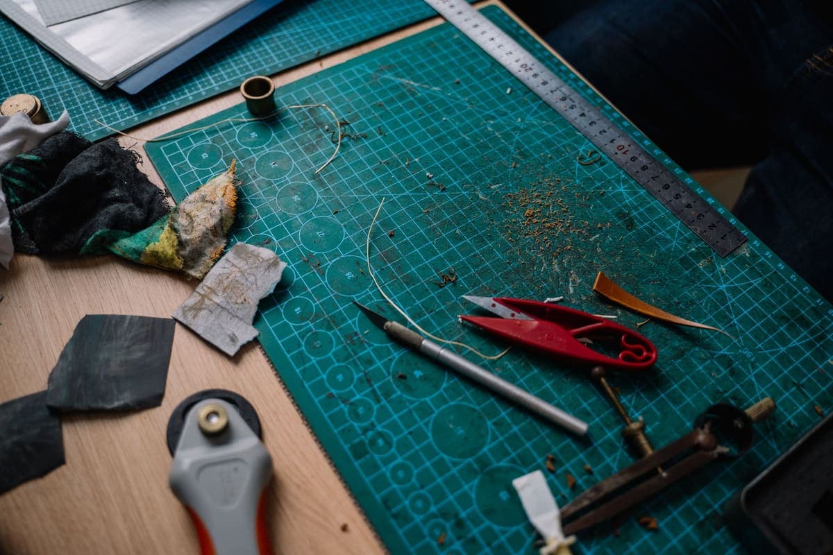 A busy craft workspace with tools and materials spread across a cutting mat