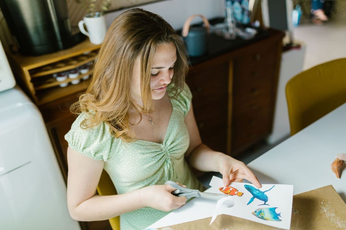 A crafter cutting out printed paper designs at a table