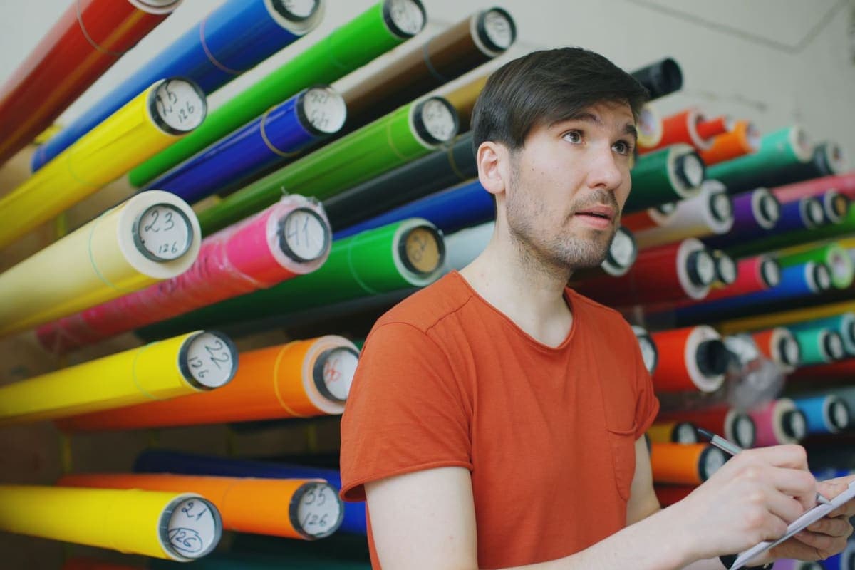 A workshop bench with rolls of colored vinyl being checked over